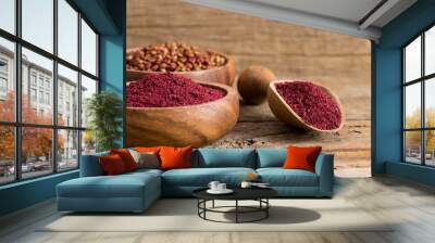 Dried ground red Sumac powder spices in wooden spoon with sumac berries on rustic table. Healthy food concept Wall mural