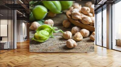 Uncooked dried chickpeas in wooden spoon with raw green chickpea pod plant on wooden table. Heap of legume chickpea background Wall mural