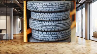 A stack of four car tires displayed on a shelf in a storage area. Wall mural