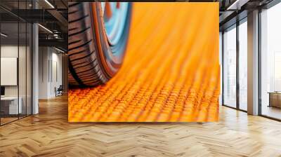 Close-up of a car tire on a textured orange surface. Wall mural