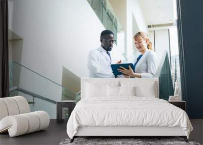 A researcher in a white coat and a female business person having a conversation in an office Wall mural