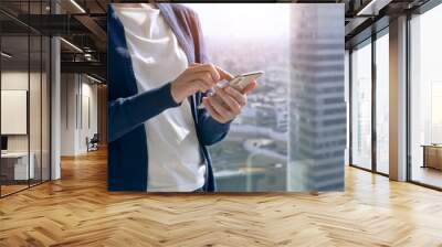 A woman operating a smartphone with the city in the background. Wall mural