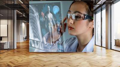 Young female doctor looking at hologram screen. Electronic medical record. Smart glasses. Medical technology concept. Wall mural