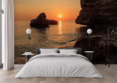 red dawn on the seashore big boulders and rocky shore wave coming ashore Wall mural