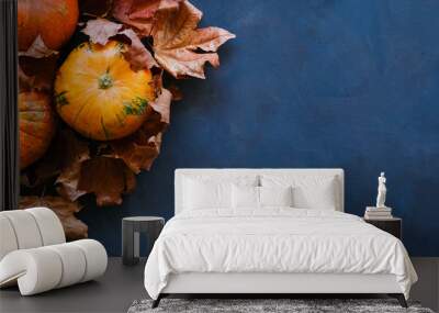 Pumpkins and autumn maple leaves on dark blue background. Thanksgiving day concept. 16x9 banner, copy space. Wall mural