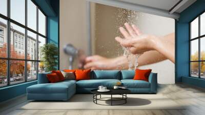 A woman uses hand to measure the water temperature from a water heater before taking a shower Wall mural