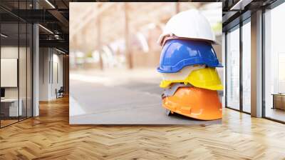 orange, yellow, blue and white hard safety wear helmet hat in the project at construction site building on concrete floor on city. helmet for workman as engineer or worker. concept safety first Wall mural