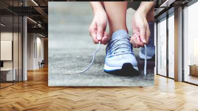 Running shoes. close up female athlete tying laces for jogging on road. Runner ties getting ready for training. Sport lifestyle. copy space banner. Wall mural