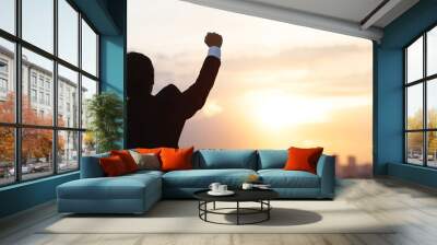 silhouette hand raised fist business man with sun lighting in morning. Wall mural