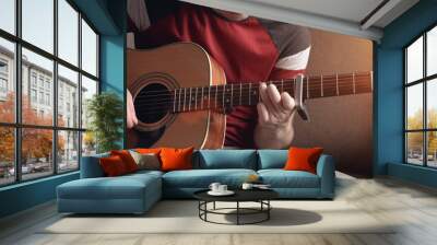 Cheerful young man is learning to play the acoustic guitar. remote online lesson. Wall mural