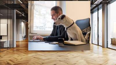 happy businessman working on laptop in office sitting next to dog with a tie Wall mural