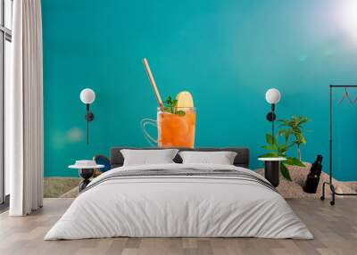 Lemonade in different glasses / jars, CBD dropper oil and a twig of marijuana plant in the sand. Sunglasses and seashells can be seen from the side.  Wall mural