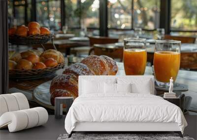 Two Croissants with Powdered Sugar on a Plate with Orange Juice and Fruit in the Background Wall mural