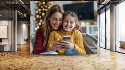 Cheerful mother and daughter using smartphone together, sitting on couch at home, shopping online on mobile phone and hugging, Generative AI Wall mural