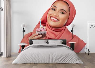 Portrait, candle in a cupcake and an islamic woman in studio on white background for dessert. Face, smile and food with a happy young muslim person eating a cake, candy or sugar snack in celebration Wall mural