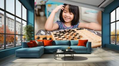 Asian kid girl and mother stay at home lockdown from covid-19 coronavirus crisis are playing chess while spending time together at home.Smart kid home school kid with mom.Stay home Stay safe with mom. Wall mural