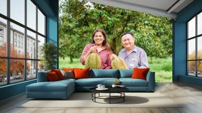 Fresh durian in Durian tree plantation,Thai senior couple farmer holding durians with happy smile for export to China- Durians are the king of fruits.Durian is delicious.Asian fruit.Economic fruits. Wall mural