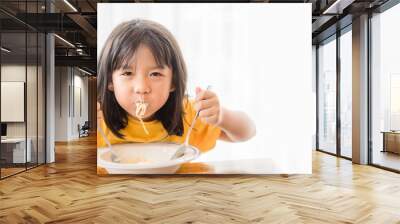 Hungry face and enjoy eating concept.Little asian girl enjoy eating with spaghetti carbonara with cheese on a plate in lunch time at restaurant.kid eating pasta.Delivery food, Delicious face. Wall mural