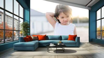 Little asian girl scratching an itch with hand outdoor.Kid's hand scratch itchy from allergy.Sensitive Skin, Food allergy symptoms, Irritation. Wall mural