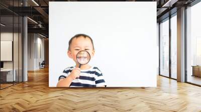 Little toddler boy child holding magnifying glass and showing front teeth with big smile on green grass: Healthy happy funny smiling face young adorable lovely boy kid with new tooth dental. Wall mural