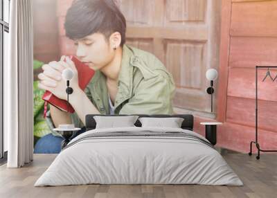 man praying on holy bible in the morning.teenager man hand with Bible praying,Hands folded in prayer on a Holy Bible in church concept for faith, spirituality and religion Wall mural