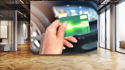 Woman hand holding  green credit card using to buy a new car. Auto business, sale concept - close up of customer hand giving credit card to buy a car Wall mural