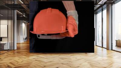 An engineer or handyman holds an orange hard hat. Close-up. Civil Engineering. Place for text. Wall mural