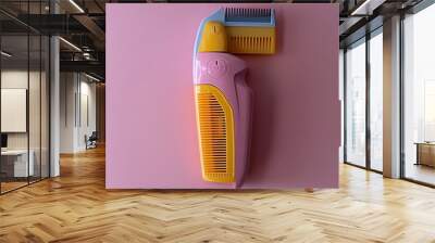 An overhead view of a pink and yellow clipper with gray plastic combs Wall mural