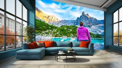 Athletic woman enjoys beautiful view on turquoise Sorapis lake with dito di dio in the background in the evening. Lake Sorapis, Dolomites, Belluno, Italy, Europe. Wall mural