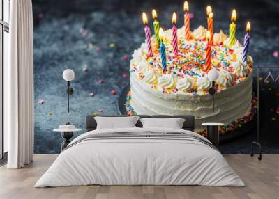 Birthday cake with lit candles and sprinkles sitting on slate background Wall mural