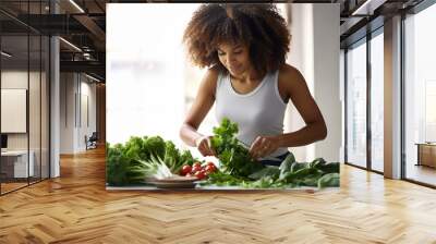 black afro american young beautiful woman with lush hair in a tank top prepares salad in the kitchen, washes lettuce, tomatoes Wall mural