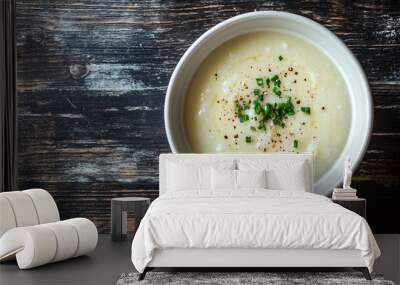 Bowl of creamy potato soup seasoned with pepper and fresh chives, served on a rustic wooden table Wall mural