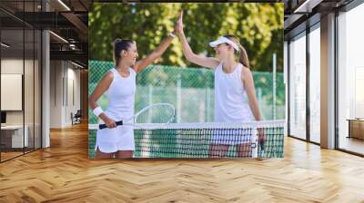 High five, success and celebrating between women tennis players training outdoors on the court. Happy, winning and fit athletes or friends playing in a friendly sports competition team building Wall mural