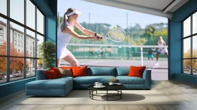 Sports and active tennis player hitting ball with racket equipment during a competitive match or hobby activity on a court. Athletic, sporty and fit woman playing in a tournament game with sportswear Wall mural