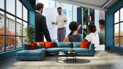 Working everyones ideas and suggestions into the plan. Shot of a young businessman leading a presentation to his colleagues in an office. Wall mural