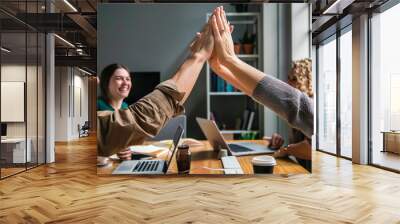 colleagues celebrating success with a high five in a modern office environment. Wall mural