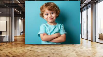 Confident young child with a mischievous grin posing against a solid blue background Wall mural