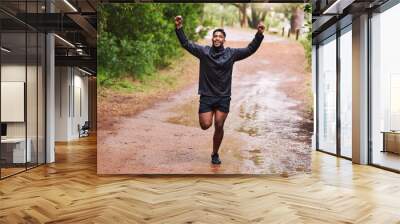 Celebrate, sports and man in nature for running, marathon training and exercise goals outdoors. Fitness, mountain and happy person with hands up for success for performance, victory and wellness Wall mural