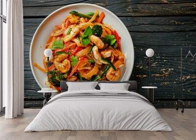 Delicious pad see ew with shrimps, broccoli, and paprika is served on a rustic wooden table on a white plate Wall mural