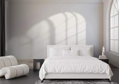 Empty room with white walls and hardwood floor, sunlight casting shadows through arched window Wall mural