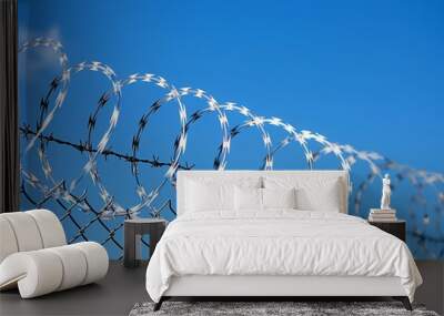 Fence with barbed wire against a background of blue sky, protected object Wall mural