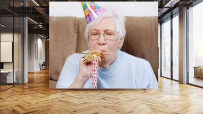 senior woman with birthday hat blowing a noise maker Wall mural