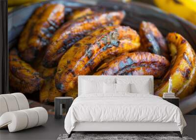 Grilled plantains, a traditional jamaican delicacy, served in a rustic woven basket with ripe bananas in the background - close-up view Wall mural