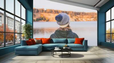 Woman in a knitted woolen hat looks at the lake Wall mural