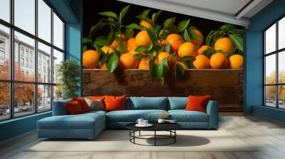 A wooden box filled with fresh oranges and green leaves in front of a solid black background Wall mural