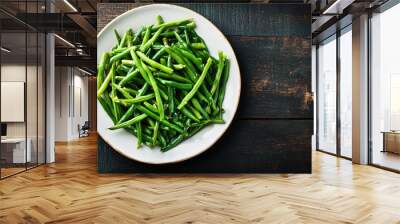 Plate of seasoned steamed green beans is placed on a rustic wooden table Wall mural