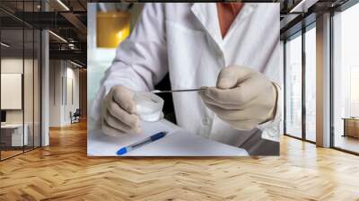 Scientist working with laboratory samples of nutritional supplements and making notes in a notebook. Wall mural