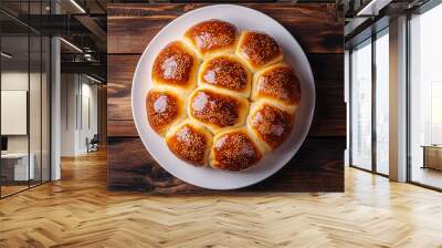 Sesame seed-studded round bread loaf on a white plate resting on a wooden table Wall mural