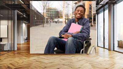 happy young disabled man in a wheelchair holding folders. Wall mural