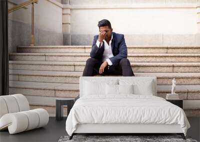 young man sitting on steps in the street with a headache Wall mural